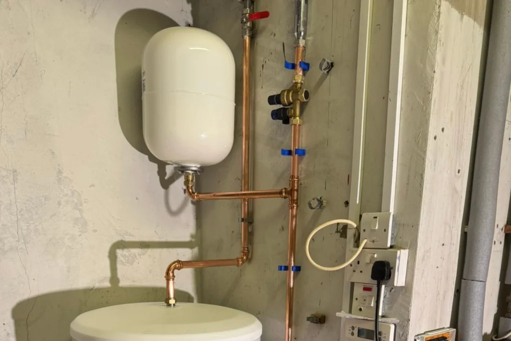 Heating expansion vessel connected to copper pipework and valves inside a property.