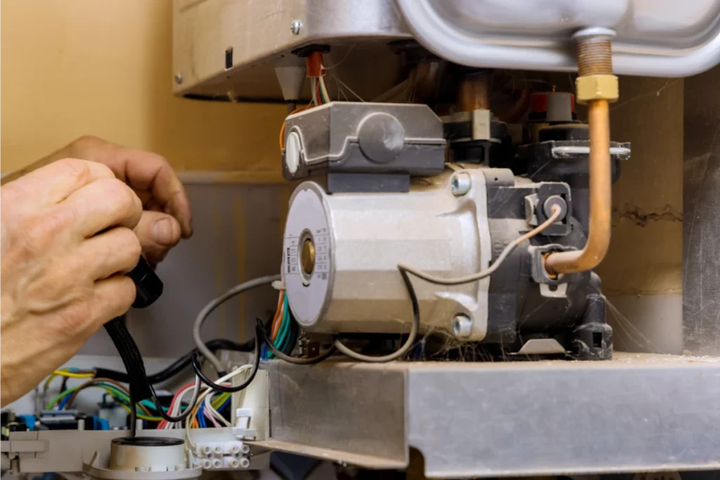 Heating engineer inspecting the circulation pump and internal mechanical components of a gas boiler.
