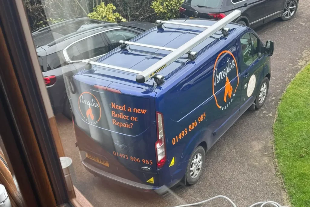 Blue Perceptive Heating service van with company branding and roof rack parked on a residential driveway.