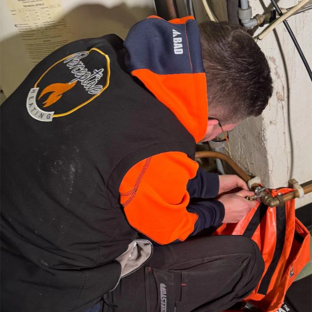 Perceptive Heating engineer working on copper pipework and plumbing connections beside a heating system.