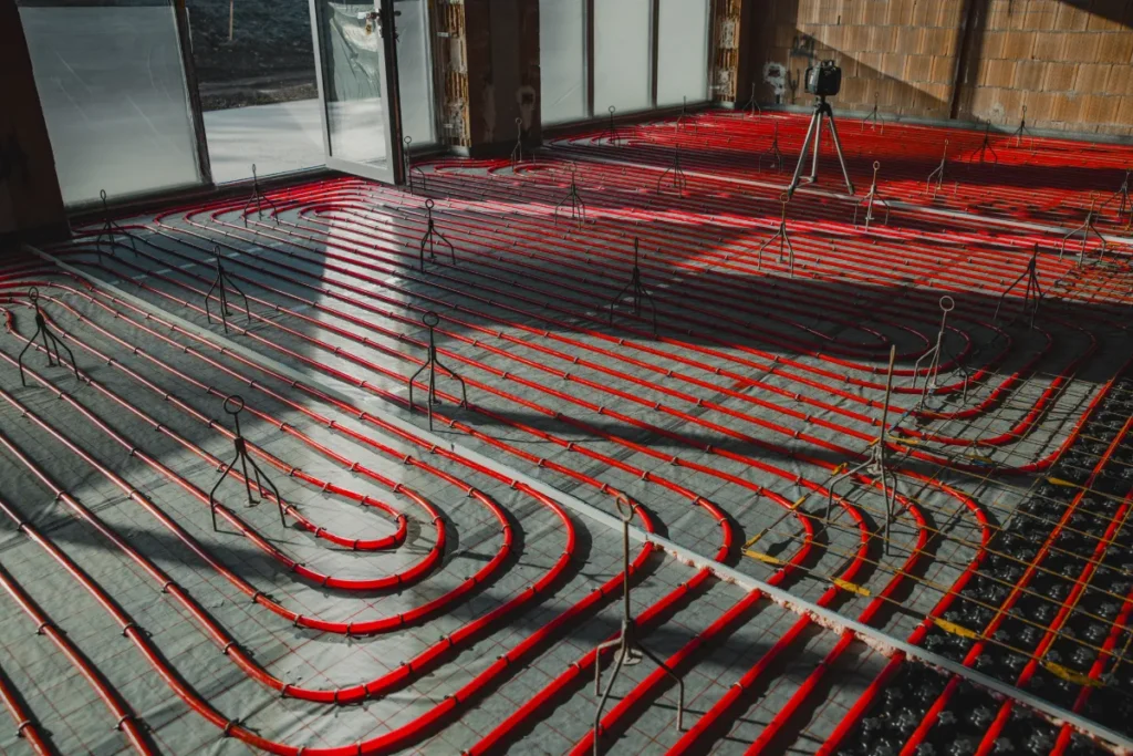 Red underfloor heating pipes arranged in loops across insulation panels during a property construction project.